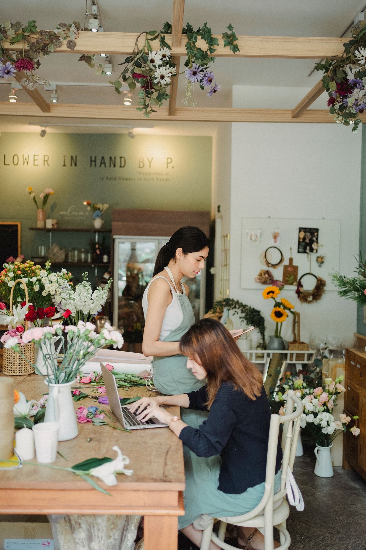Two florists managing work together at the counter of their flower shop
