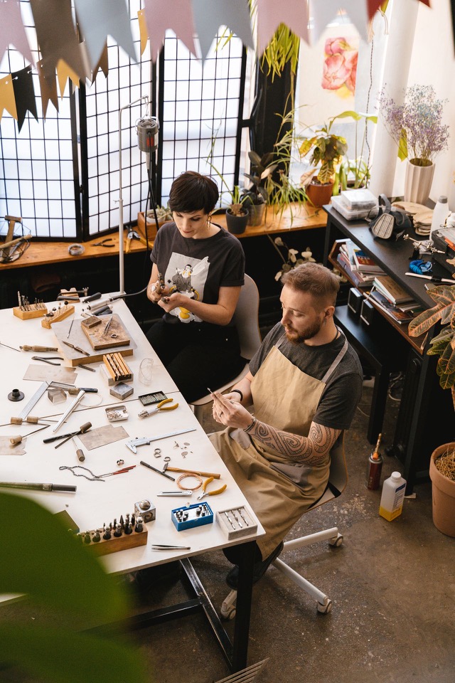 Two craftspeople making jewelry together in their workshop